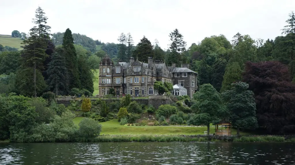 Charming historic castle surrounded by lush gardens and a tranquil lake, perfect for travel and nature enthusiasts.