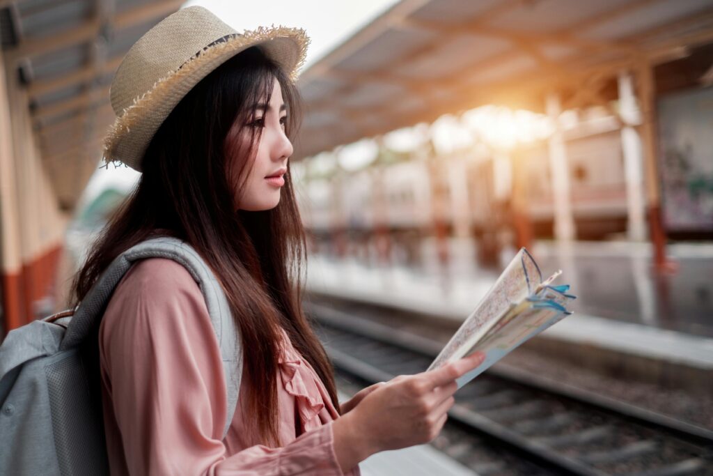 A stylish woman with a map at a train station, ready for adventure.