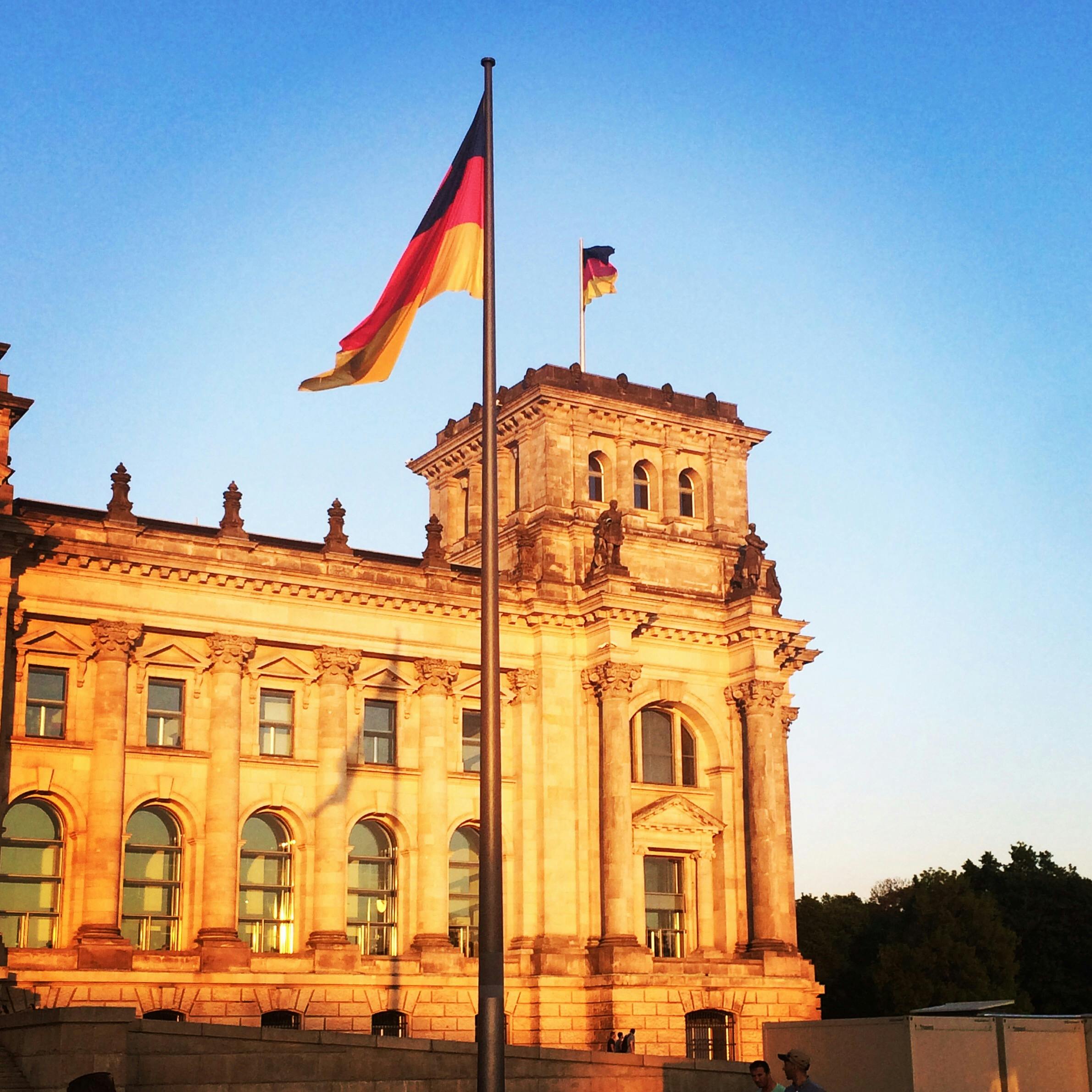 The German Reichstag building with flags during a picturesque sunset in Berlin, Germany.
