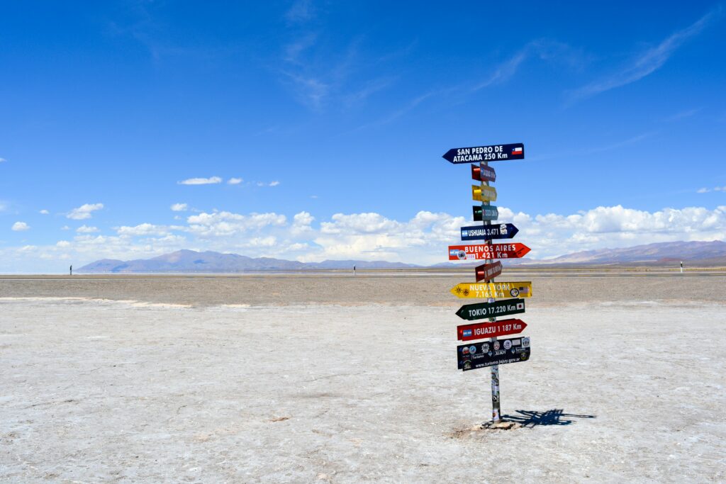 A bright signpost stands in a vast arid landscape with clear blue skies in Argentina.