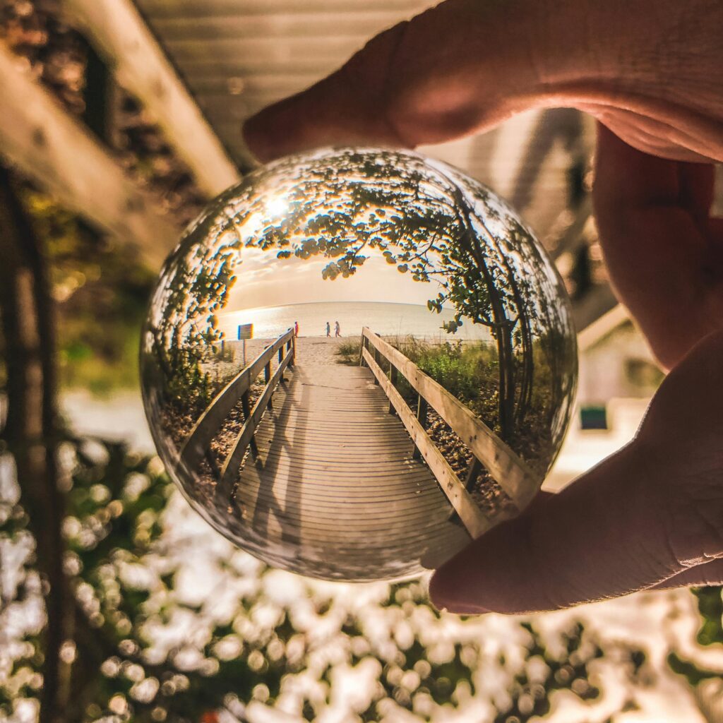A unique view of Bonita Springs beach captured through a crystal ball, highlighting a walkway and ocean view.