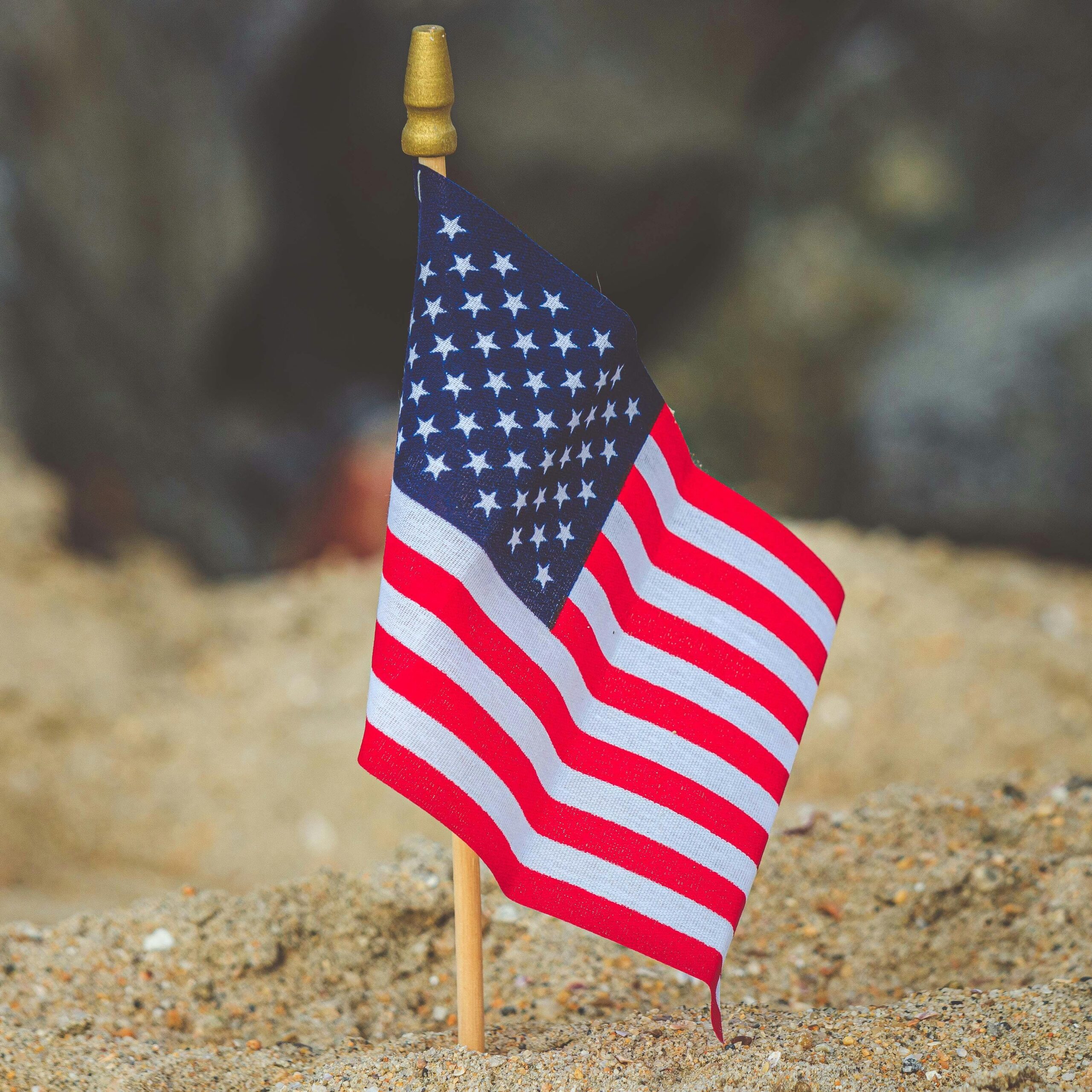 American flag on a sandy beach, emphasizing patriotism and summer vibes.