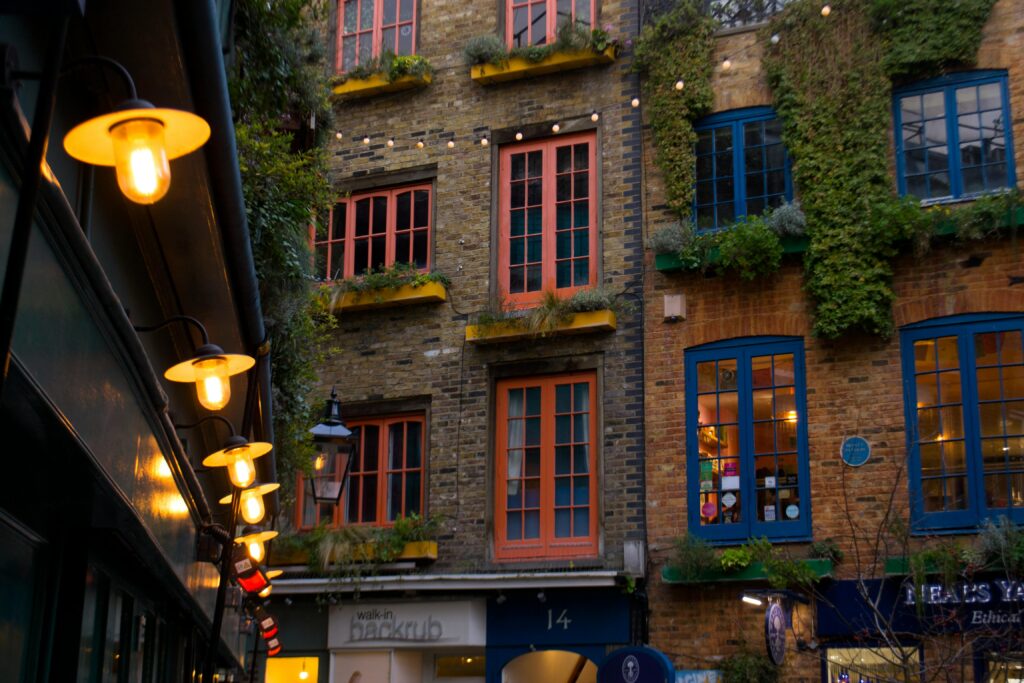 Illuminated Neal's Yard facade in London's Covent Garden with string lights and lush greenery.