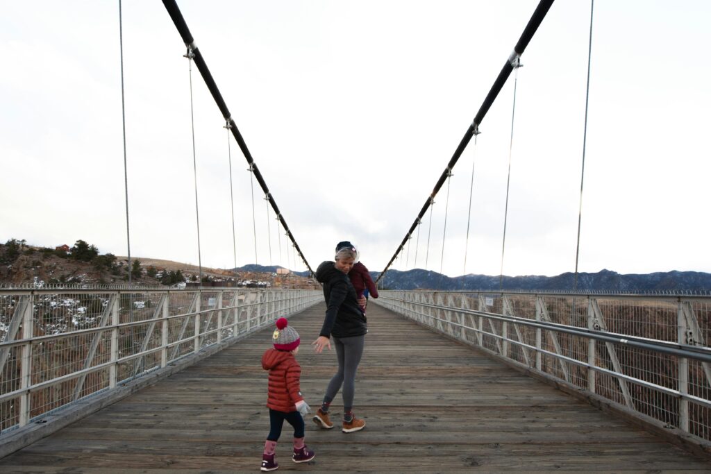 Mother with children on a scenic suspension bridge in a winter landscape.