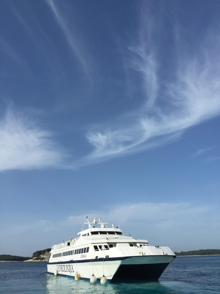 A sleek ferry cruising under a bright blue sky, showcasing modern maritime travel.