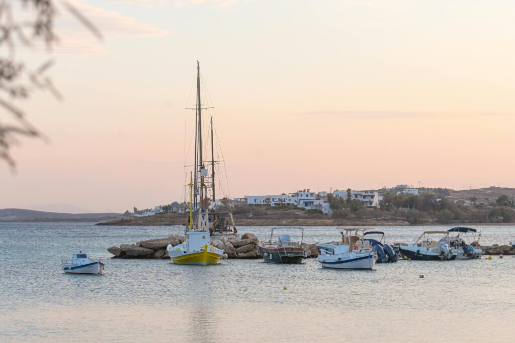 Beautiful sunrise view of boats moored at Aliki Bay, Greece, with calm waters and distant houses.