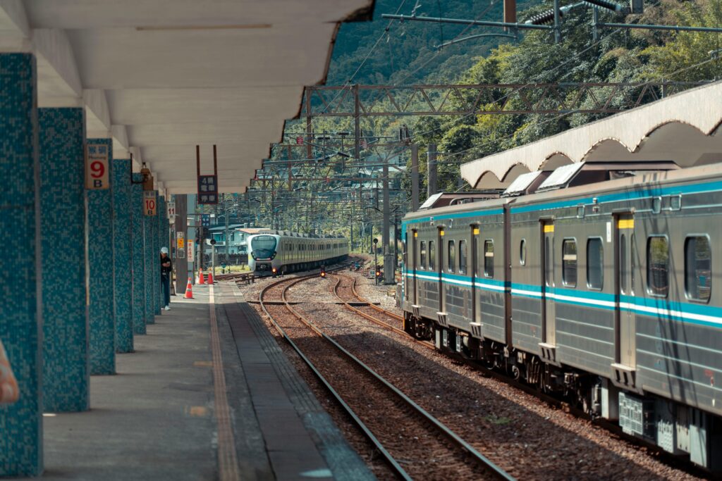 Passenger train approaching a scenic railway station surrounded by nature, capturing modern transport.