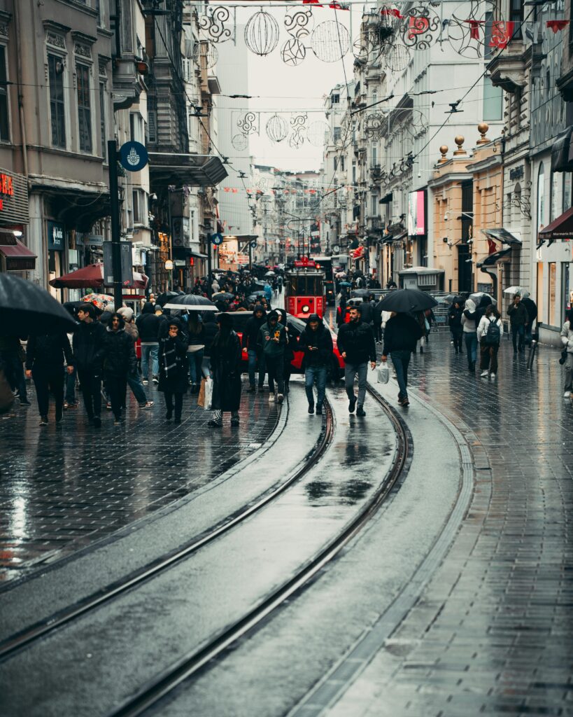 Crowded İstiklal Avenue in İstanbul on a rainy day with people walking and iconic tram.