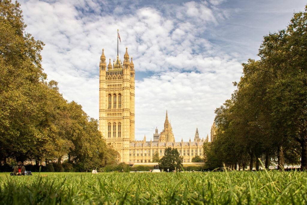 Westminster Palace framed by trees on a sunny day in London park.