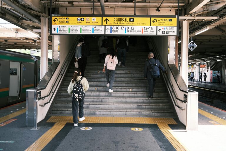 People ascending stairs at a Tokyo railway station, emphasizing city life and public transportation.