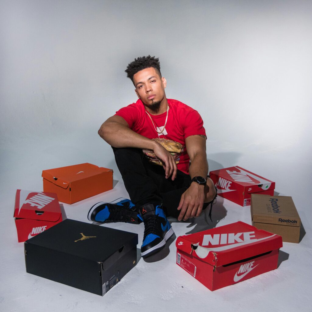 Stylish male model posing with popular shoe brands in a studio setting.