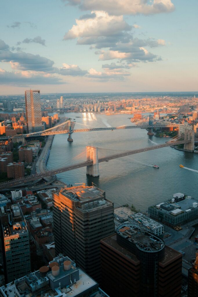 Stunning aerial cityscape of New York City featuring the iconic Brooklyn Bridge and skyline at sunset.