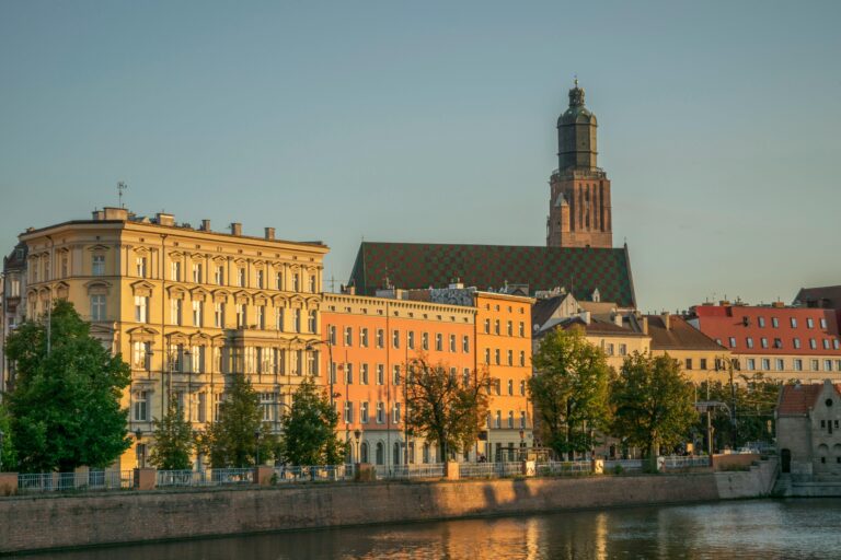 Capture of Wrocław's colorful townhouses and historic church by the Odra River at sunset.