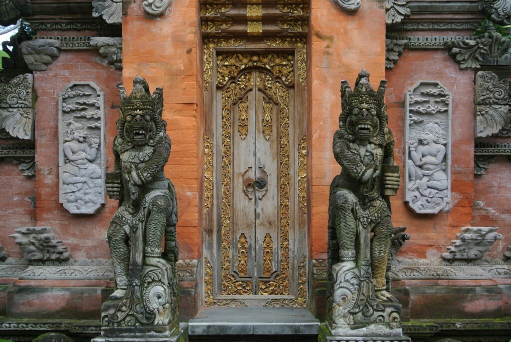 Capturing the ornate entrance of a Balinese temple in Ubud with detailed stone carvings and golden accents.