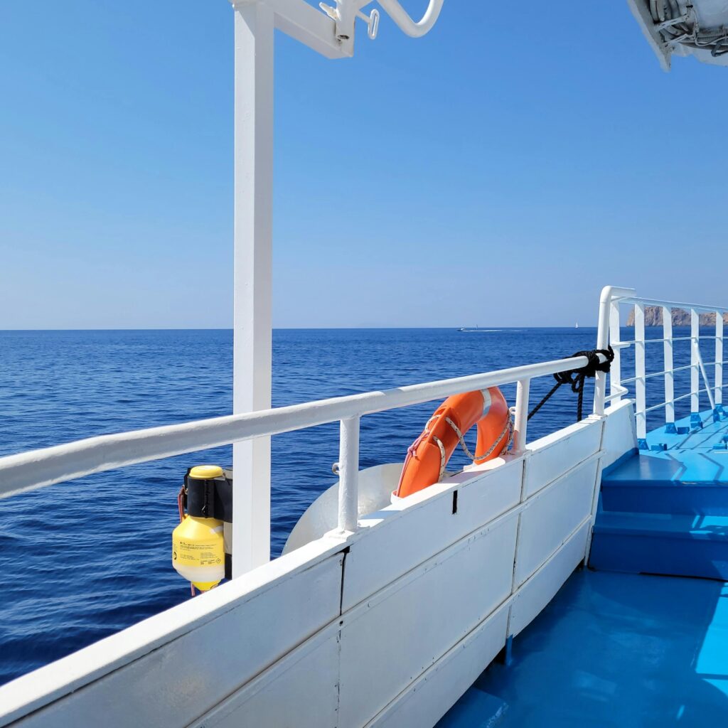 Serene view from a cruise ship deck over a calm, blue sea under a clear sky.