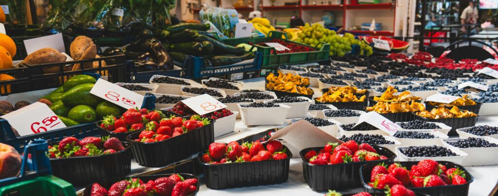 A colorful display of fruits and vegetables at a lively market stall.