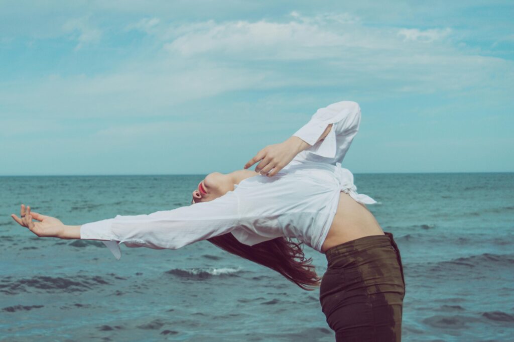 A woman performing a yoga pose by the ocean, capturing a moment of balance and tranquility.