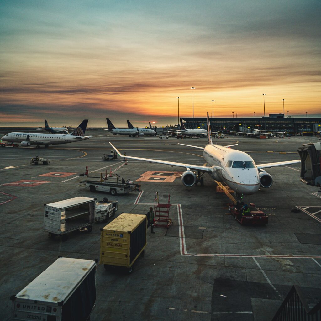 Airplanes parked at a busy airport terminal during sunset, showcasing aviation and travel.