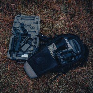 Aerial view of a camera and accessories on grass, showcasing photography gear outdoors.