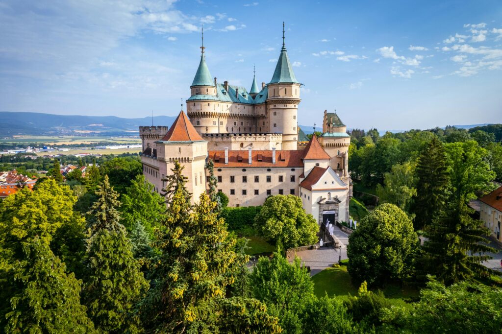 Stunning aerial shot of Bojnice Castle surrounded by lush greenery in Trenčiansky kraj, Slovakia.