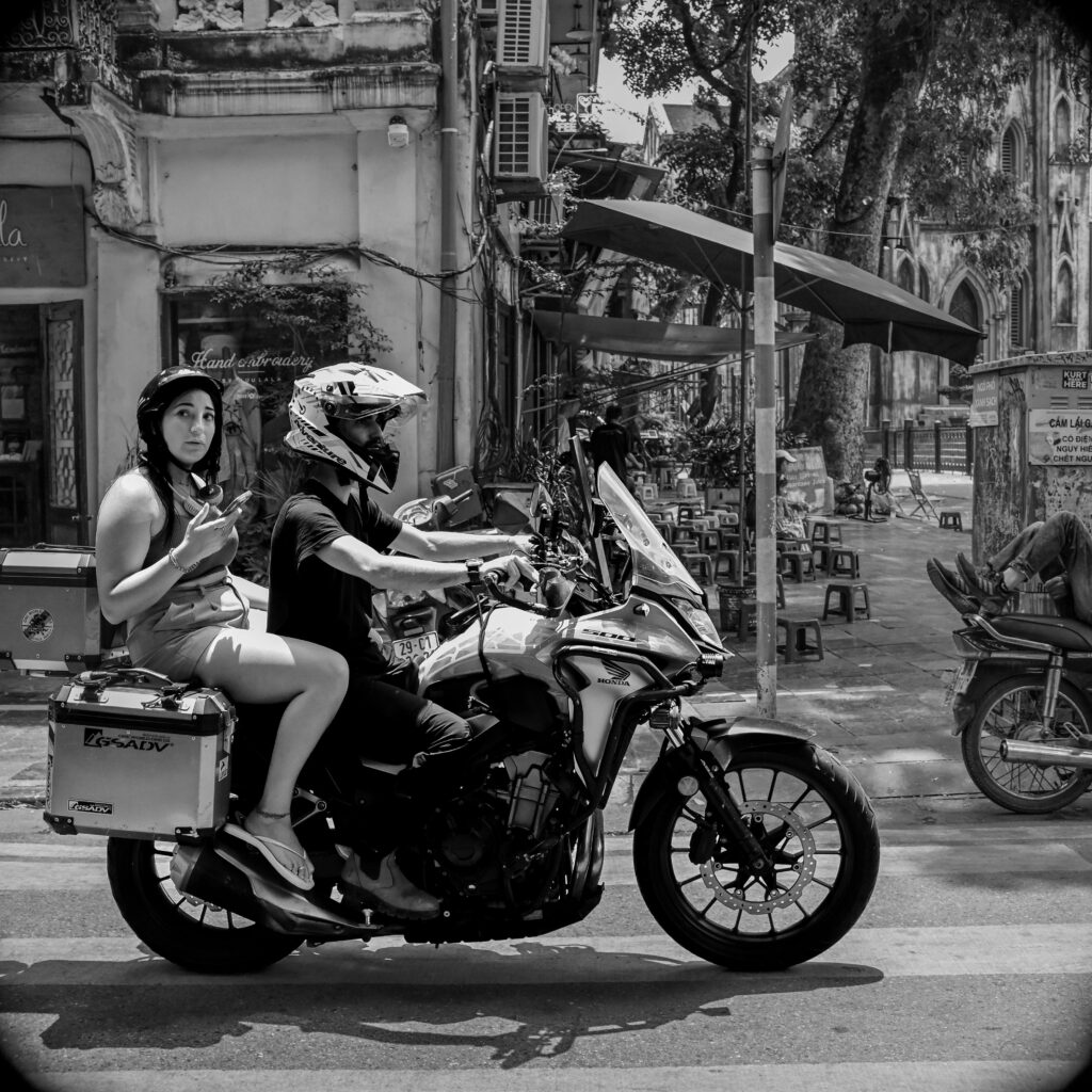 pexels-photo-31962579-31962579 Black and white scene of two riders on a scooter in a bustling Vietnamese street.