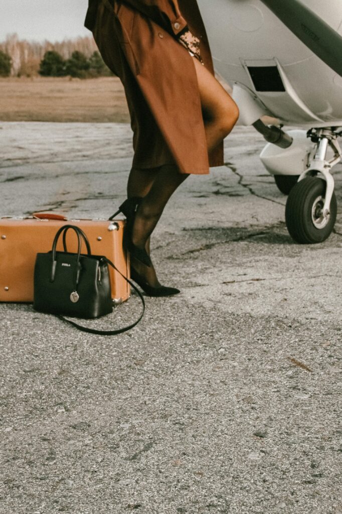 Elegantly dressed woman beside a private plane with luxury luggage. Travel and sophistication.