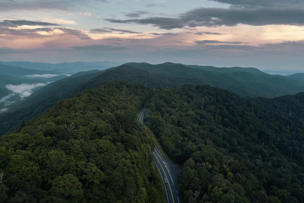A breathtaking aerial view of a winding road through the lush Smoky Mountains at sunrise, perfect for adventure and travel themes.