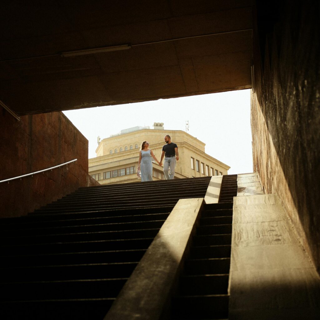 A couple walking up the steps of a tunnel in Yerevan, Armenia, with architectural background.