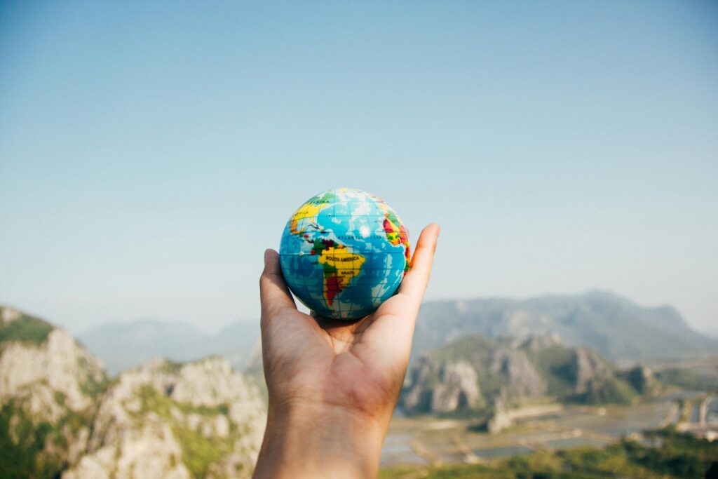 pexels-photo-346885-346885 Hand holding a globe against a mountain background symbolizing travel and exploration.