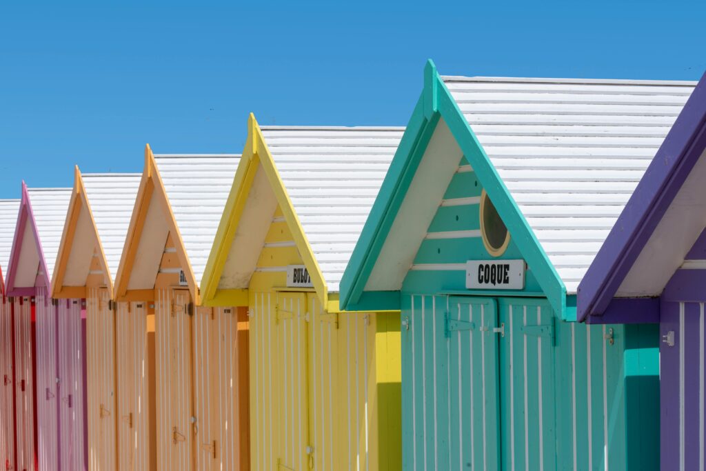 A row of colorful beach huts under a clear blue sky, exemplifying summer vibrancy.
