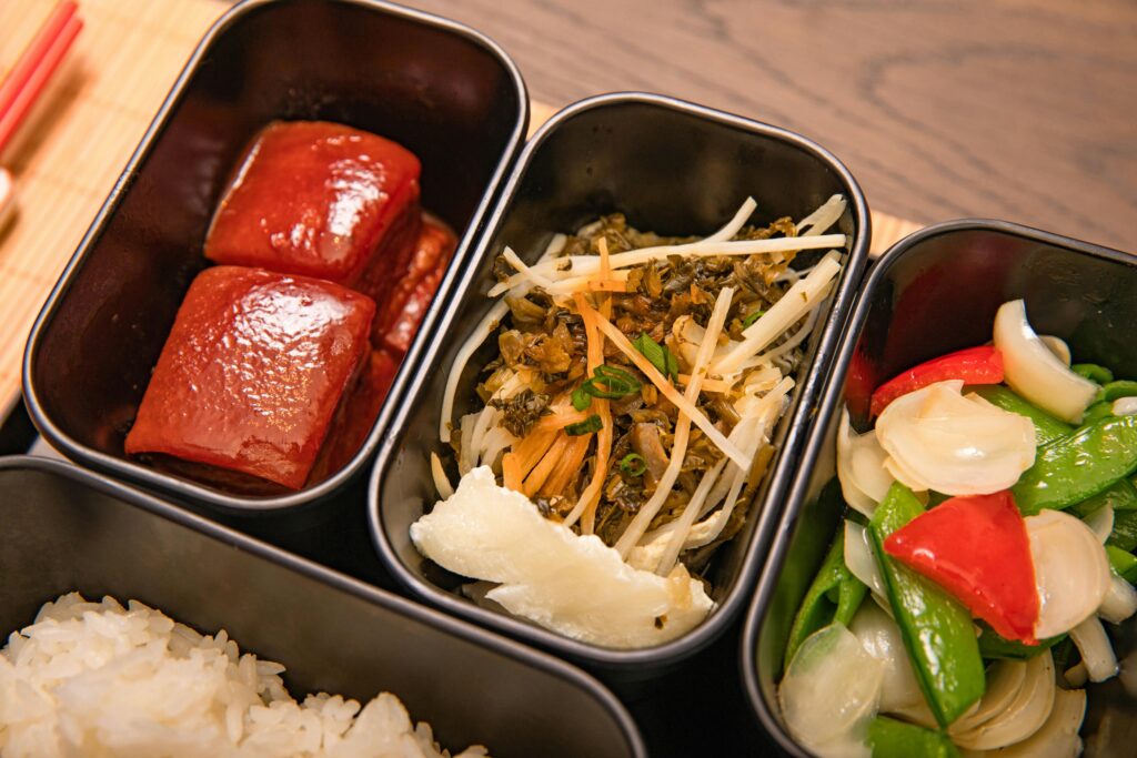 Colorful Asian lunch bento box with vegetables, meat, and rice.