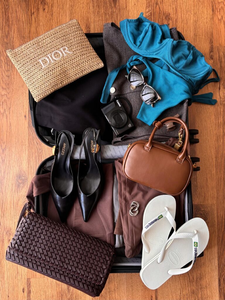 pexels-photo-35335645-35335645 Flat lay of fashion and travel essentials in an open suitcase on wooden floor, ready for vacation.