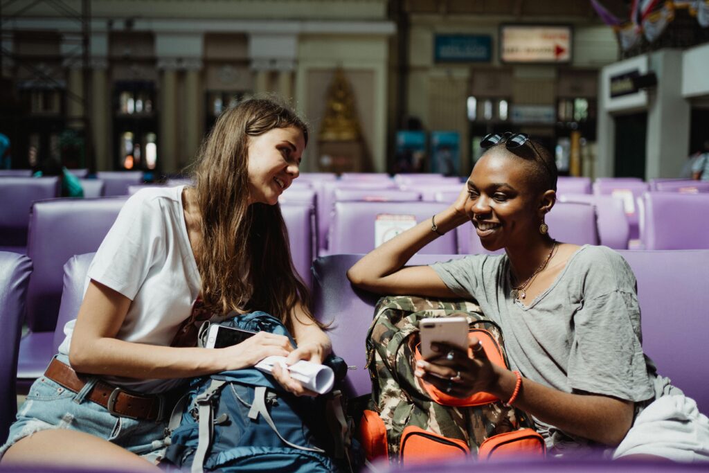pexels-photo-4901948-4901948 Two travelers enjoy a conversation while waiting at a train station, backpacks in hand.