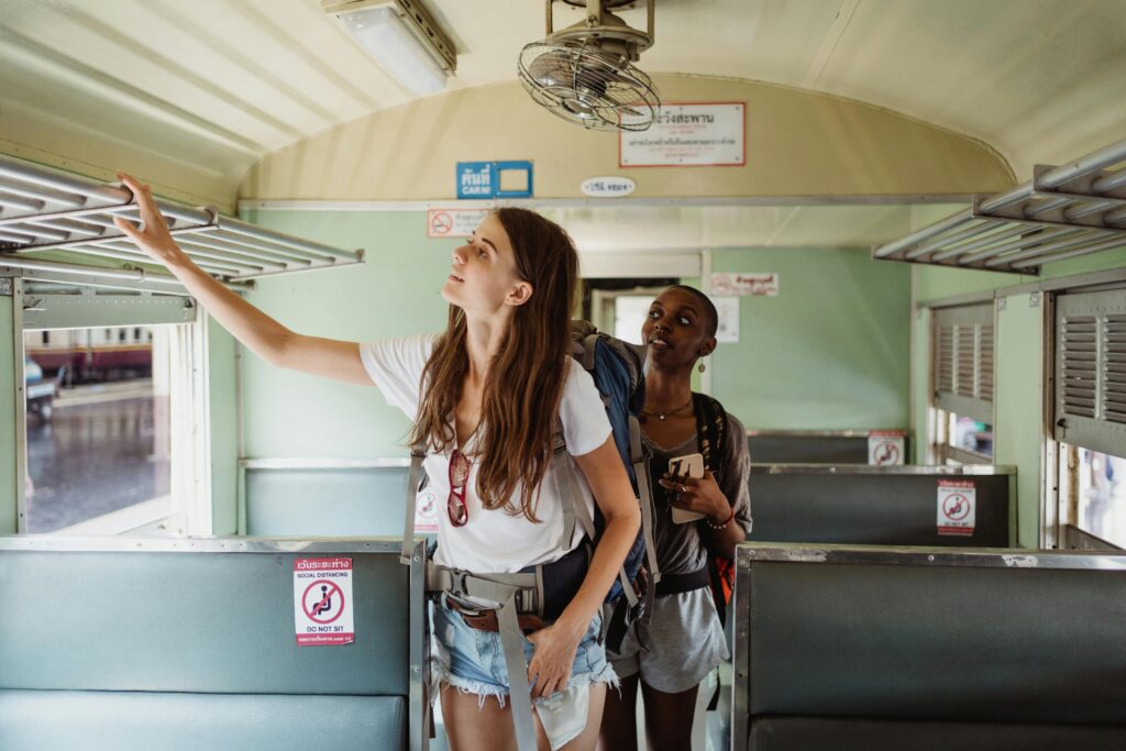Two women backpackers inside a train carriage setting luggage, enjoying adventure travel.