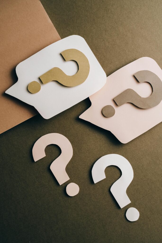 Artistic paper cutouts of question marks creating a conceptual design on a brown surface.