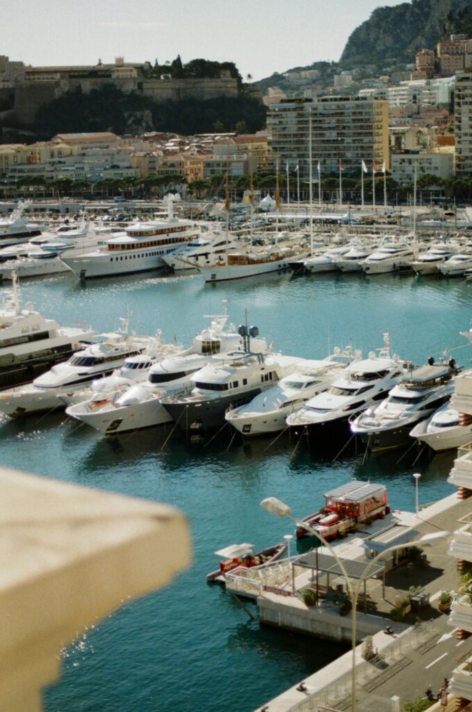 Aerial view of Monaco harbor filled with luxurious yachts and cityscape backdrop showcasing opulence.