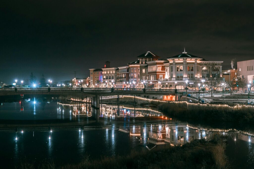 Illuminated buildings reflecting off the Napa River at night, creating a serene cityscape.