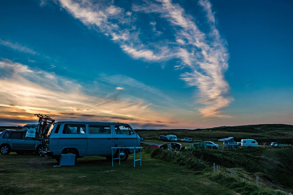 A scenic sunset view of Volkswagen campervans parked in Durness, Scotland.