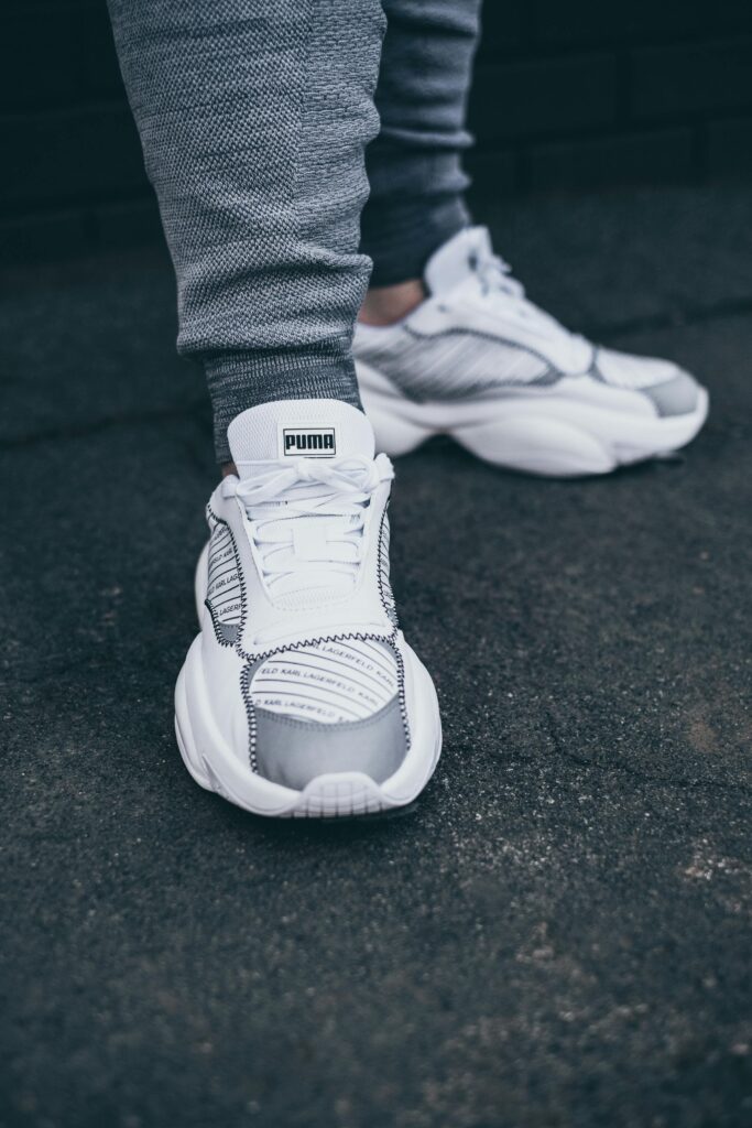 pexels-photo-6777988-6777988 Detailed close-up of PUMA white sneakers on a textured asphalt surface, emphasizing modern footwear style.