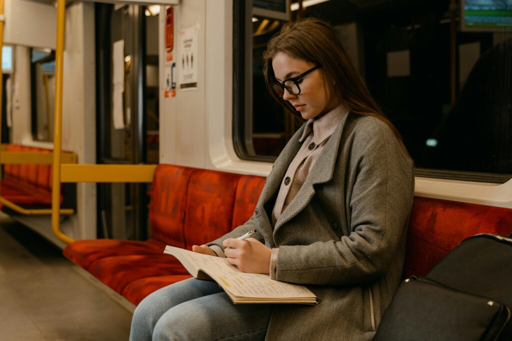 A young woman focusing on her studies while traveling on a quiet train ride.