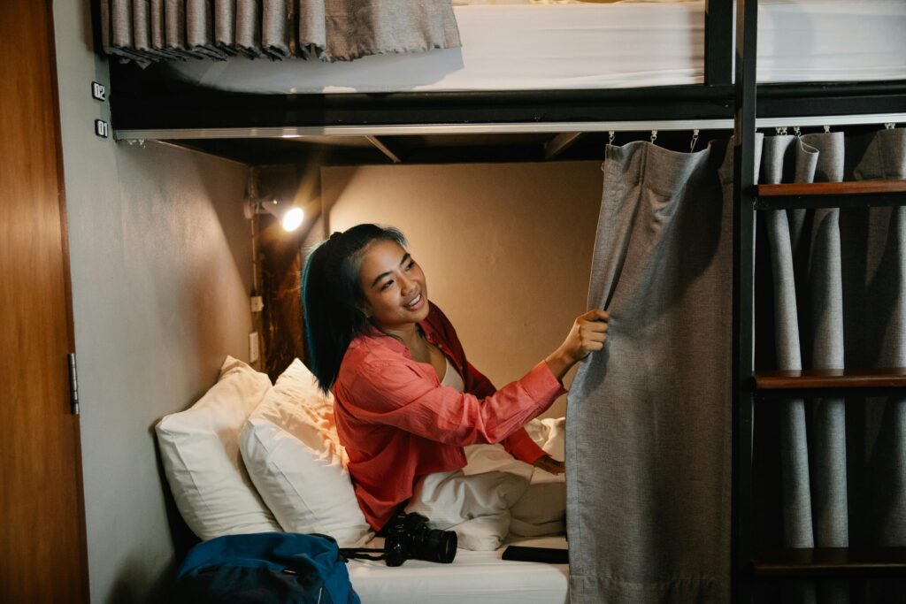 Young woman enjoys comfort in a cozy hostel bunk bed, surrounded by soft lighting.