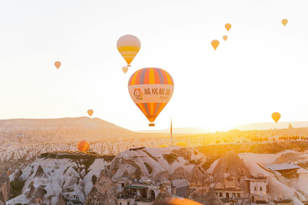 Colorful hot air balloons soar over Cappadocia's landscape during sunrise, offering a mesmerizing view.