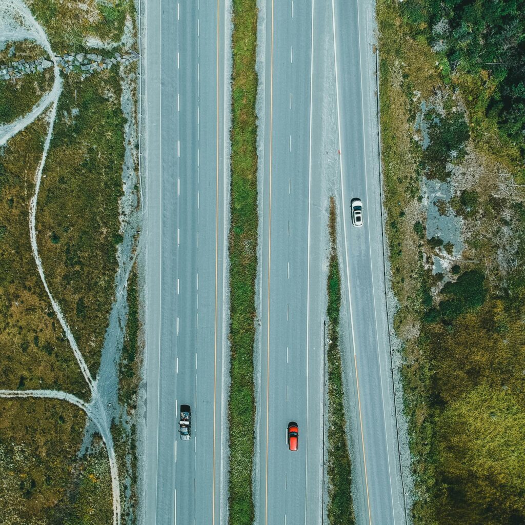 Drone shot of a highway with cars surrounded by green landscape, ideal for travel themes.