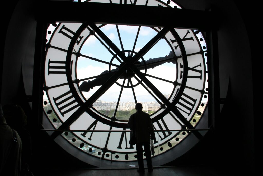 Silhouette standing inside the Musée d'Orsay clock, overlooking Paris skyline.