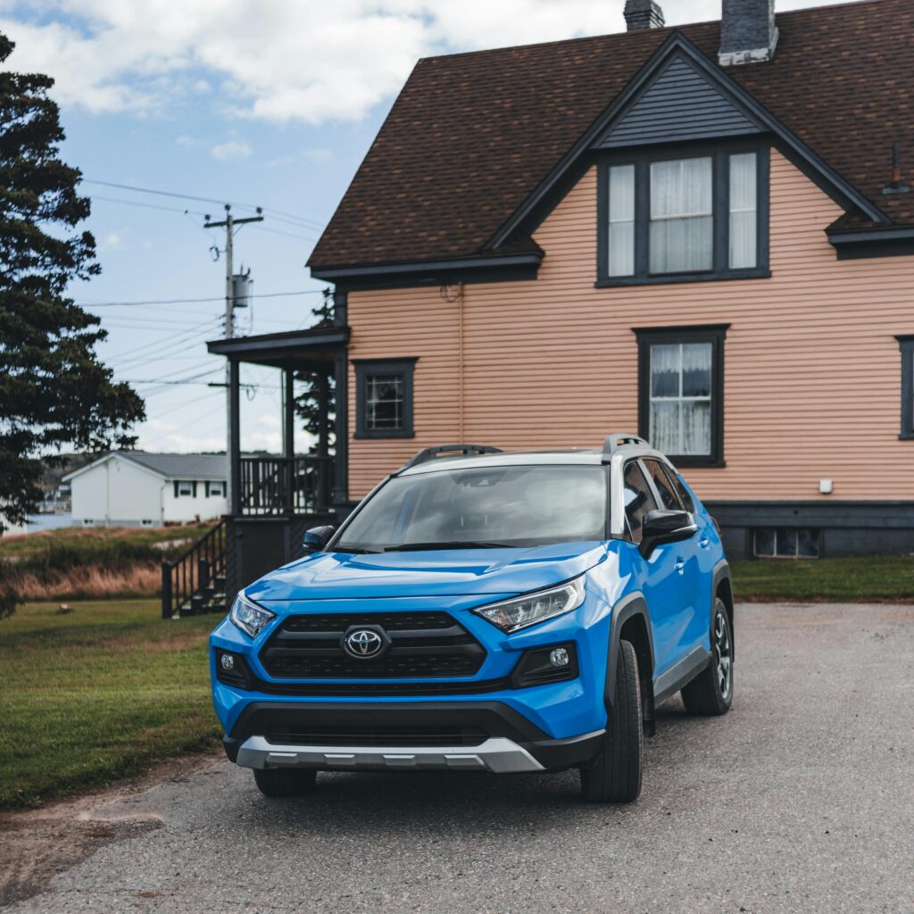 Blue Toyota SUV parked in front of a traditional house on a clear day.
