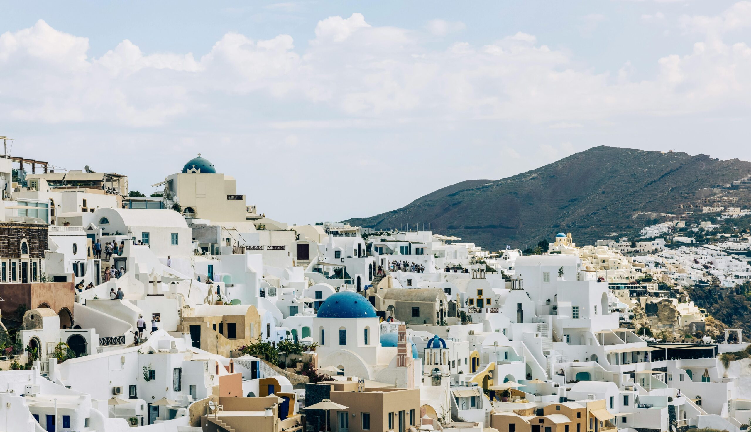 Stunning view of Santorini's white-washed buildings and blue domes under a cloudy sky.