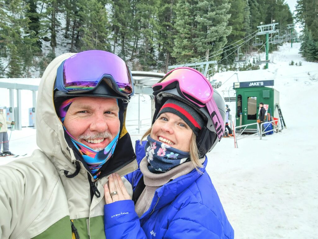 A happy couple in ski gear poses at Sundance Resort ski lift, Utah.
