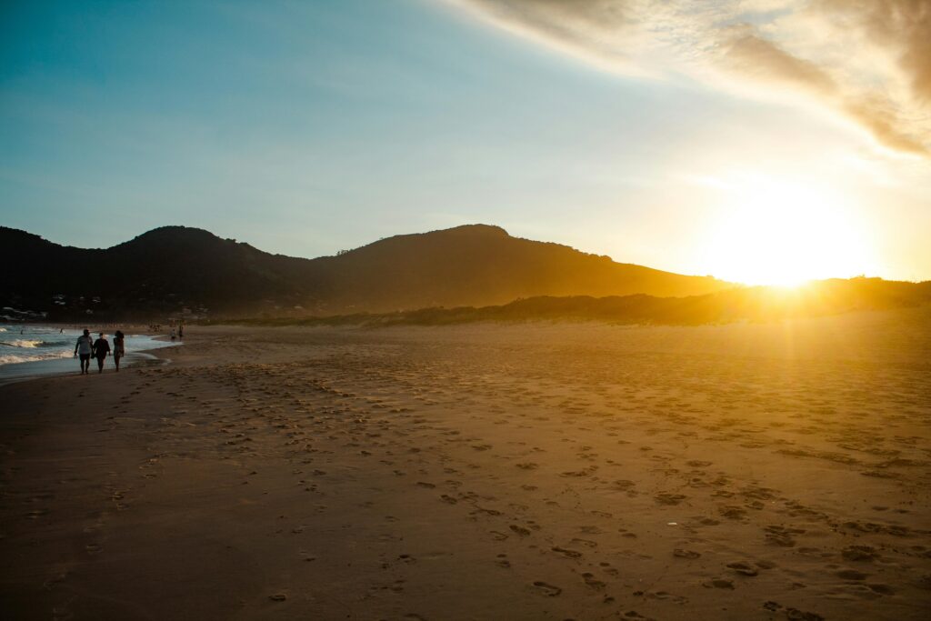 Breathtaking sunset at Gamboa Beach in Santa Catarina, Brazil, with golden sands and distant mountains.