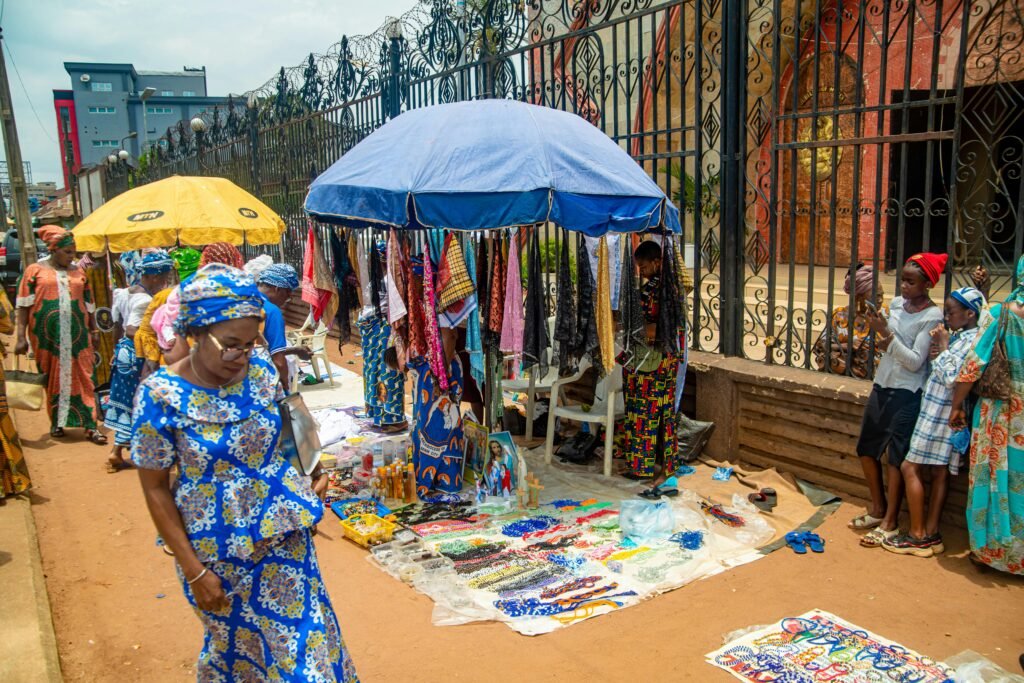 Colorful outdoor market scene in Benin City, Nigeria, showcasing vibrant fabrics and local merchandise.