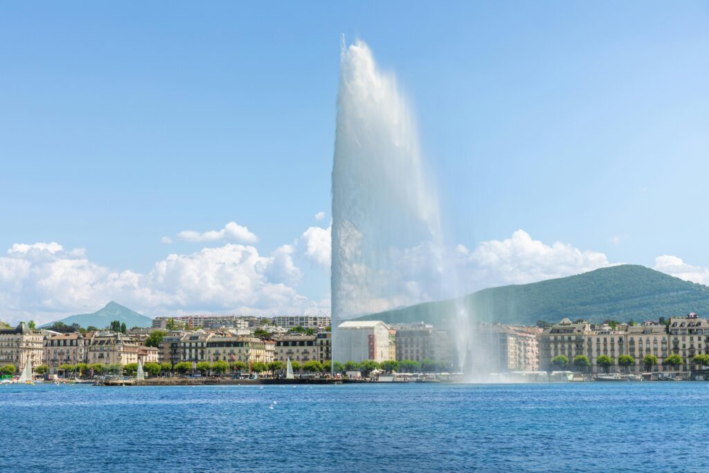 Captivating view of Jet d'Eau fountain in Geneva against a backdrop of clear skies and mountains.